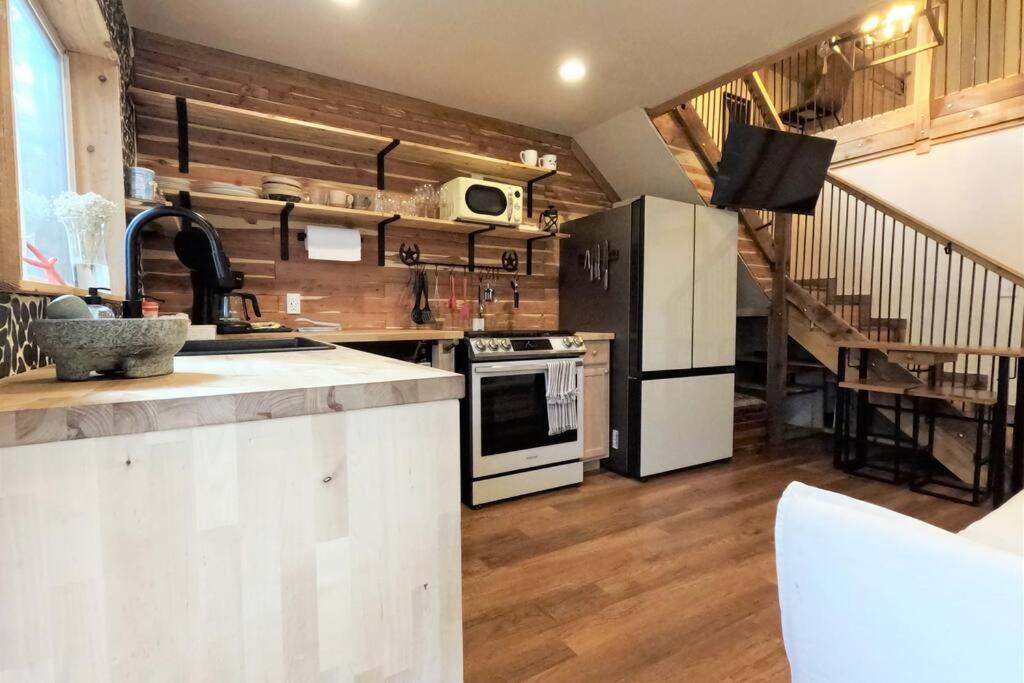 a kitchen with white appliances and a staircase at Cozy Coop Casita - Lake Travis-Hot Tub-Tiny House in Austin