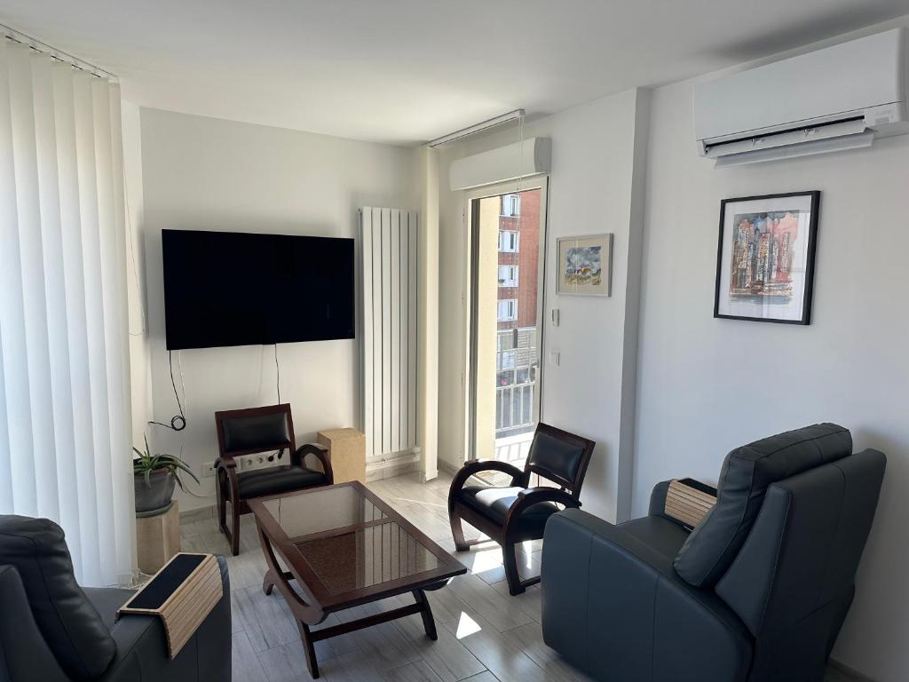 un salon avec un canapé, des chaises et une télévision dans l'établissement Bright sunny flat 2 bedrooms 750 sqft + free PKG, à Saint-Ouen