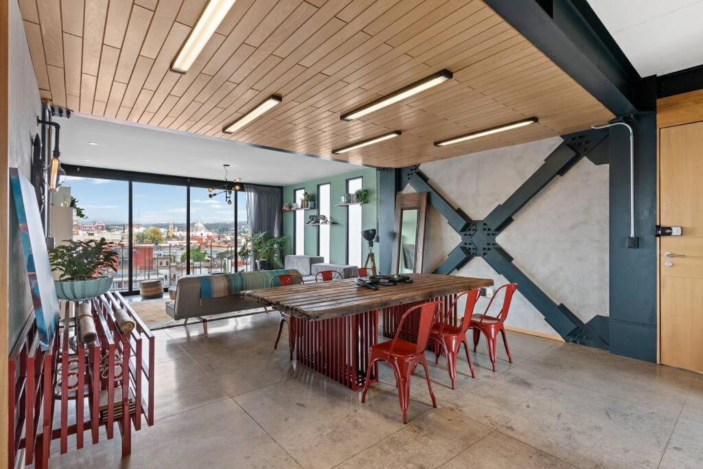 a dining room with a wooden table and red chairs at Penthouse nuevo con terraza en zona centro historico in Puebla