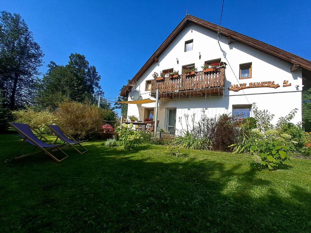 a house with a balcony and two chairs in the yard at Nasz Zakątek in Mysłakowice