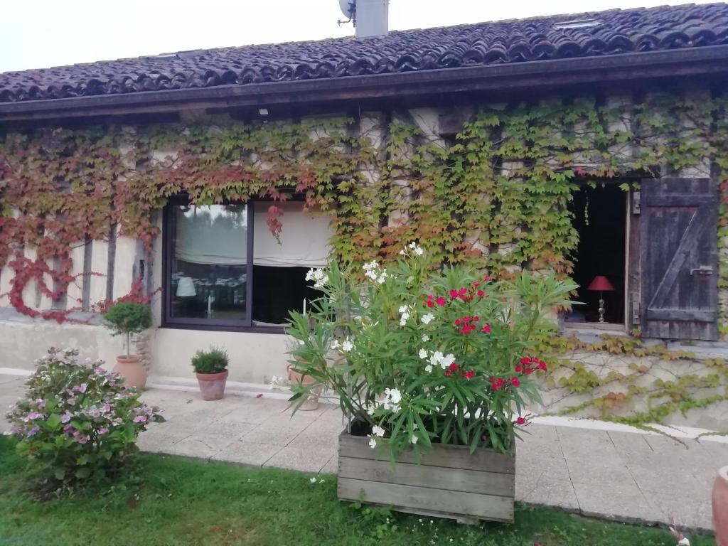 una casa ricoperta di edera con fiori nel cortile di Le Chai de Serres a Artassenx