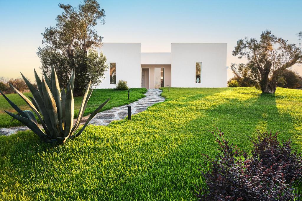 a large white house with a green yard at Villa 'Tenuta Quattro Volpi' in Melendugno