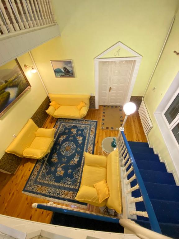 a living room with yellow furniture and a staircase at Хостел Особнячок in Bishkek