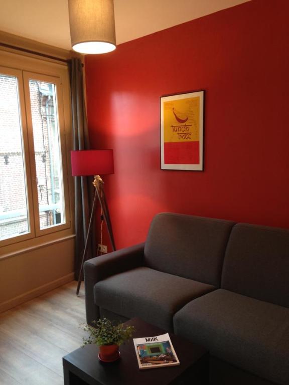 a living room with a couch and a red wall at Côté Saint-Léonard - Honfleur in Honfleur