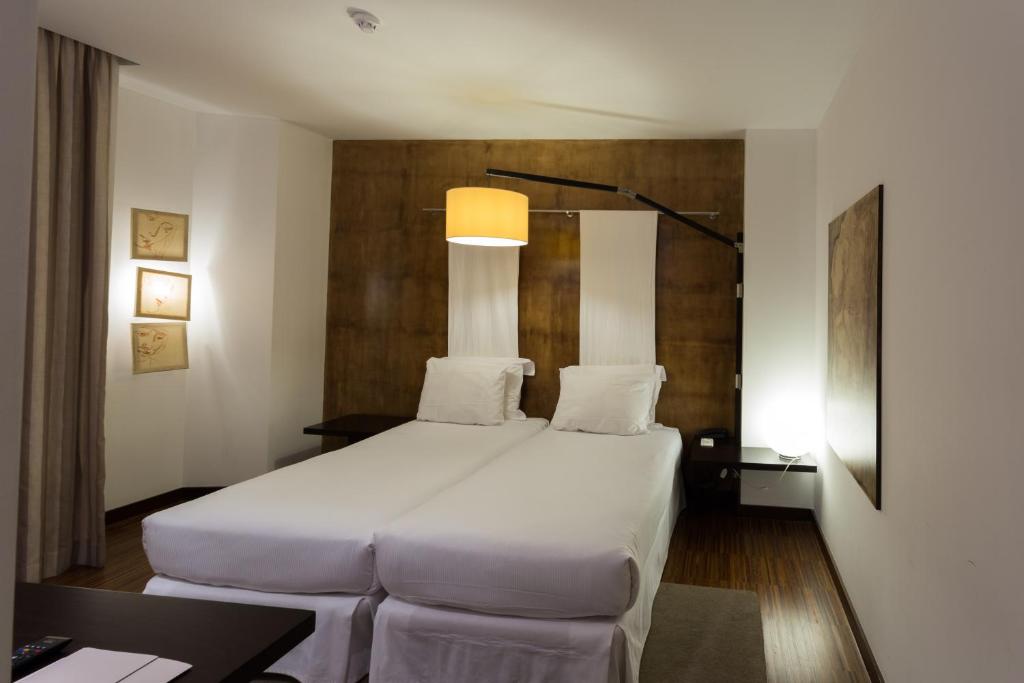 a bedroom with a large white bed and a desk at Porto Trindade Hotel in Porto