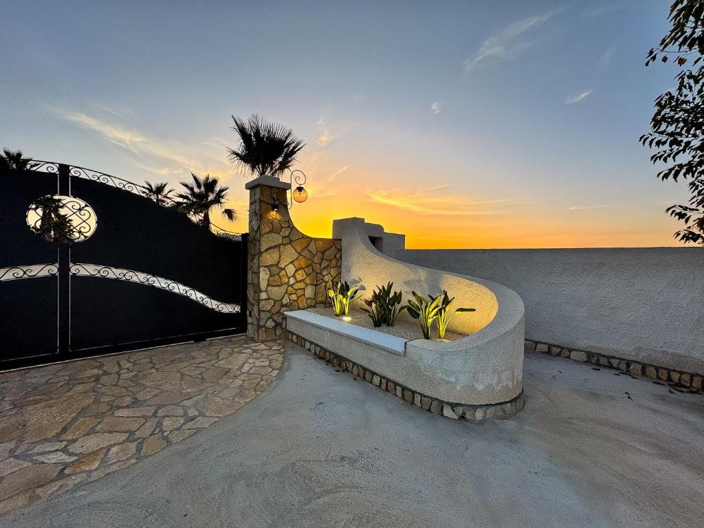 un tramonto sull'oceano con una panchina di pietra di Casa Vacanze Il Vigneto a Marsala
