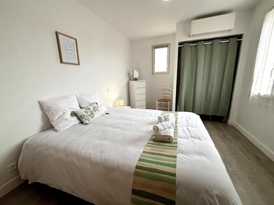 een slaapkamer met een groot wit bed met 2 schoenen erop bij L'Océane, studio spacieux avec place de parking, Proche plage in La Palud