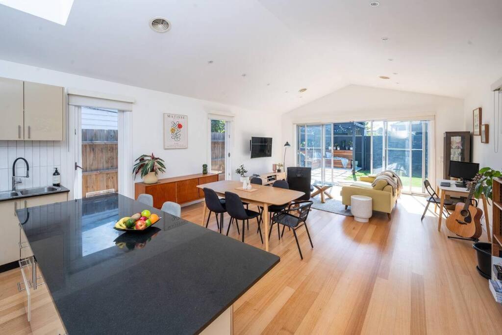 a kitchen and living room with a table and chairs at Spacious light-filled 3BD sanctuary in Northcote in Melbourne