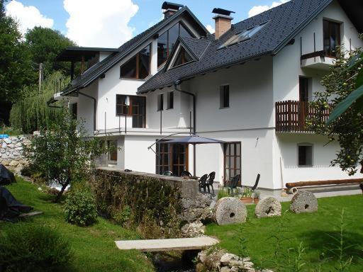 uma casa branca com um cão preto sentado à frente dela em The Millhouse Bled em Bled
