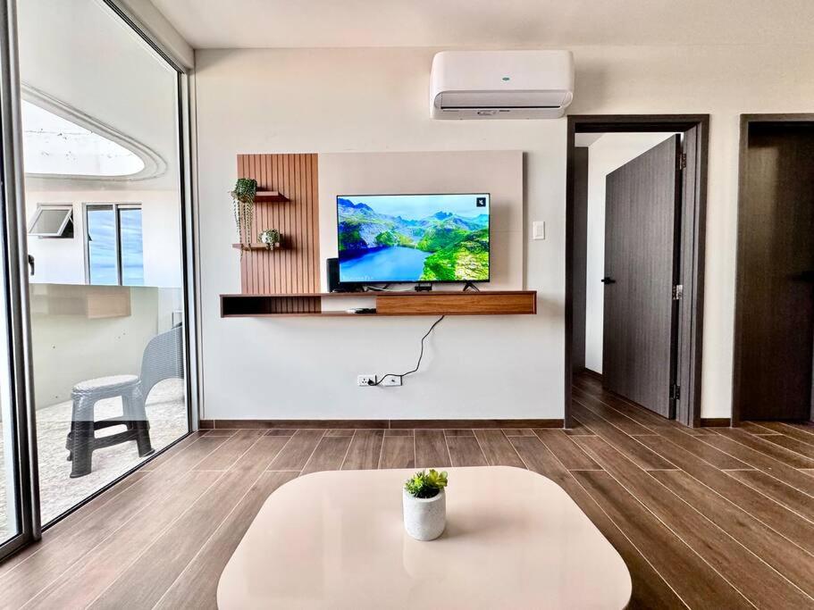 ein Wohnzimmer mit einem Fernseher an der Wand in der Unterkunft Apartamento Lujoso y Comodo con la mejor vista panoramica de Santa Cruz in Hamacas