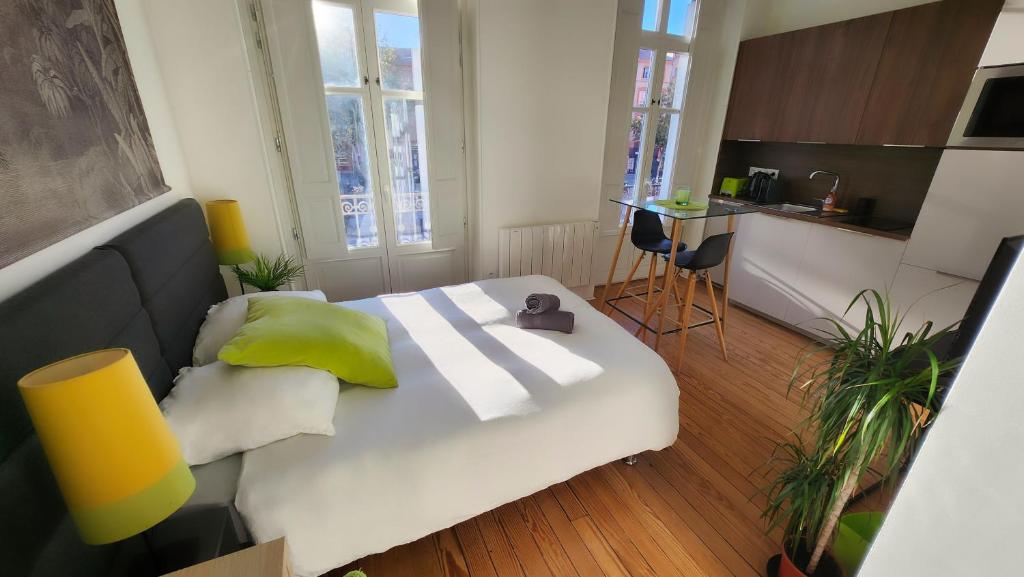 - une chambre avec un grand lit blanc et des oreillers jaunes dans l'établissement Le Jardin d'Éden Premium - équipé, balcon, hypercentre, à Toulouse