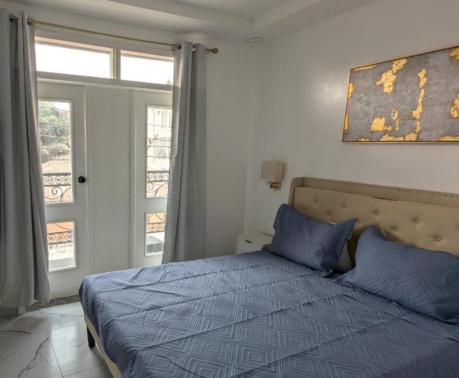 KinshasaにあるL F Suitesの青いシーツのベッドと窓のある寝室