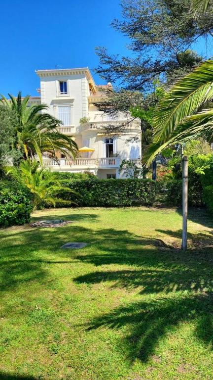 une grande maison blanche avec un palmier dans une cour dans l'établissement Emplacement exceptionnel pour 4 personnes, à Boulouris-sur-Mer