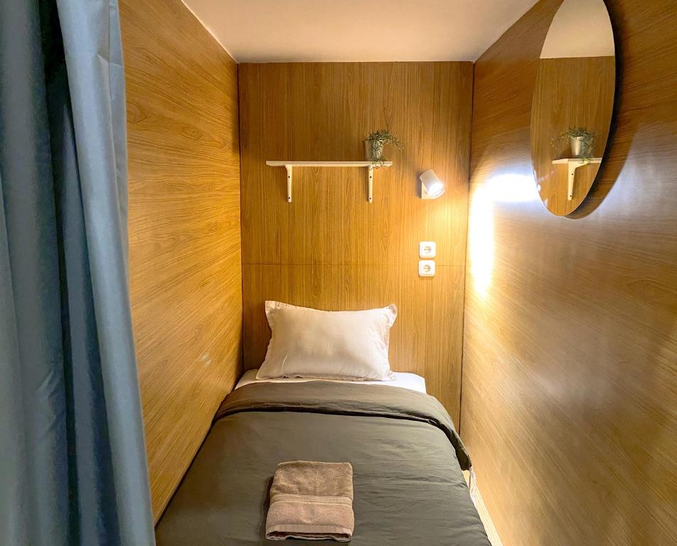 a small bed in a small room with wooden walls at Snooze Malang in Malang