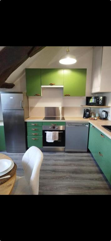 une cuisine avec des armoires vertes et une cuisinière four supérieur dans l'établissement La cachette cosy, à Nevers