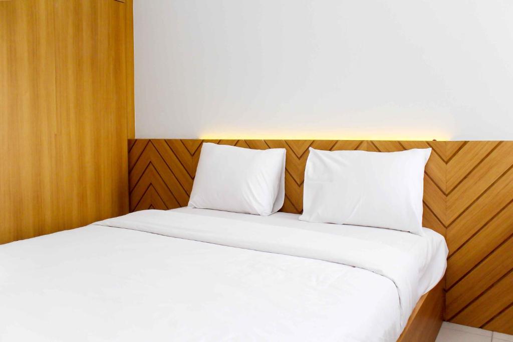 two beds in a hotel room with white sheets at Fancy and Elegant Studio at Patraland Urbano Apartment By Travelio in Bekasi