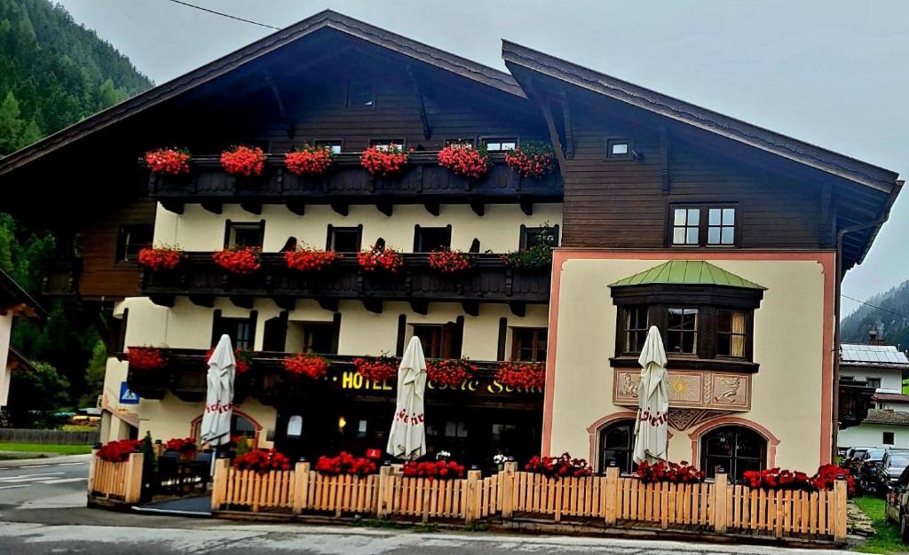 a building with flower boxes and flags in front of it at Hotel Restaurant Liesele Sonne in Sankt Leonhard im Pitztal