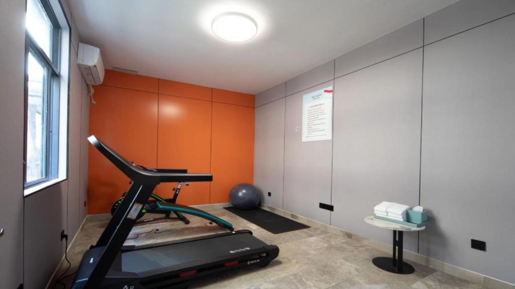 a room with a treadmill and an orange wall at 宜尚酒店 日月广场骑楼老街店 in Haikou