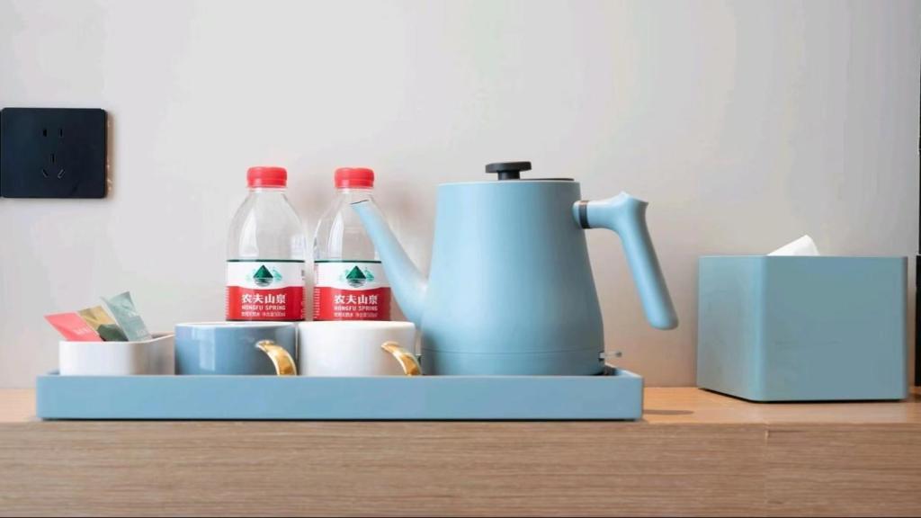 a coffee maker and bottles of soda on a table at 宜尚酒店 日月广场骑楼老街店 in Haikou