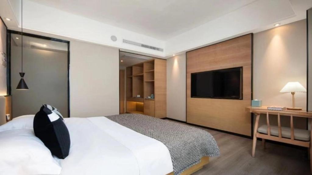 a bedroom with a large bed and a television at 宜尚酒店 日月广场骑楼老街店 in Haikou