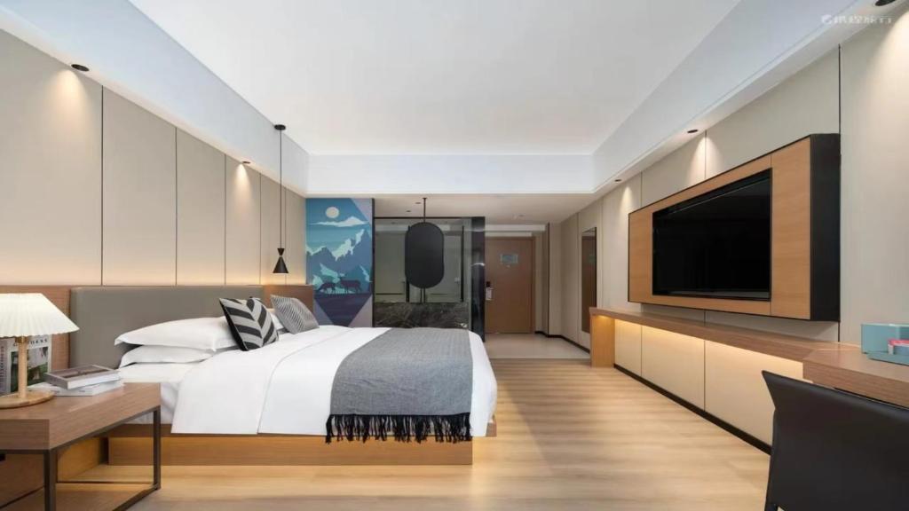 a bedroom with a large bed and a flat screen tv at 宜尚酒店 日月广场骑楼老街店 in Haikou