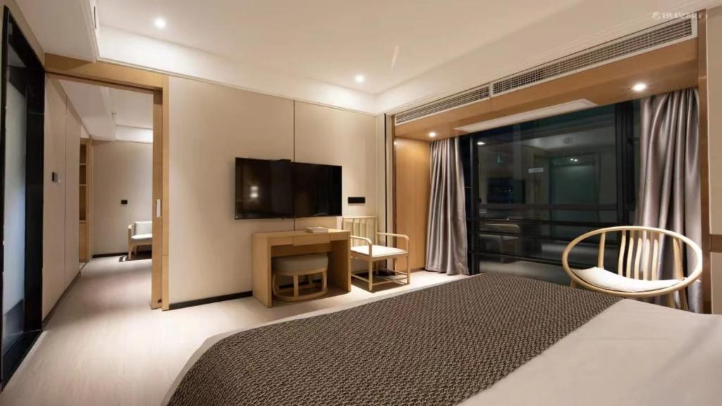 a bedroom with a bed and a flat screen tv at 宜尚酒店 日月广场骑楼老街店 in Haikou