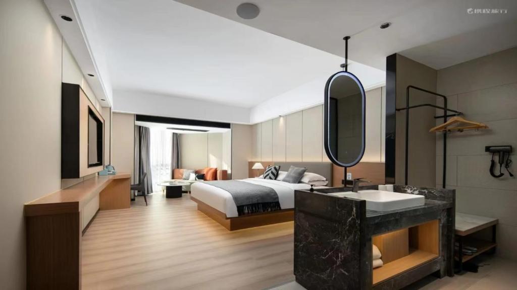 a bedroom with a bed and a sink and a mirror at 宜尚酒店 日月广场骑楼老街店 in Haikou