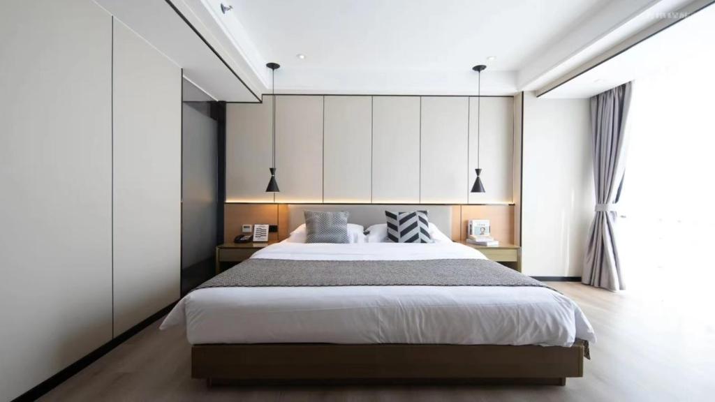 a bedroom with a large bed and a large window at 宜尚酒店 日月广场骑楼老街店 in Haikou
