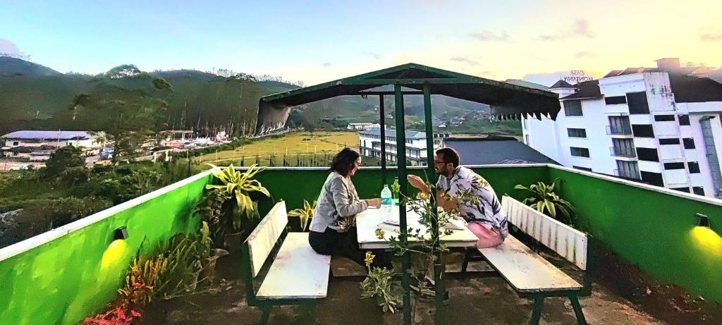 a man and a woman sitting at a table on a roof at Greenview holiday inn in Munnar