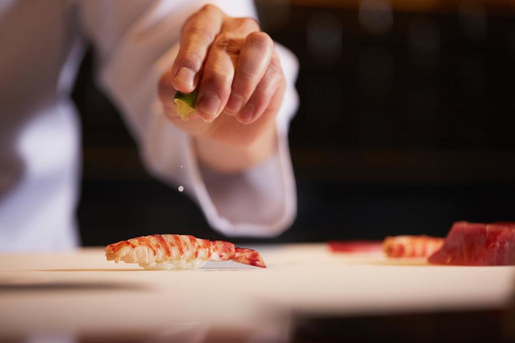 a person is holding a piece of shrimp on a plate at JW Marriott Hotel Nara in Nara