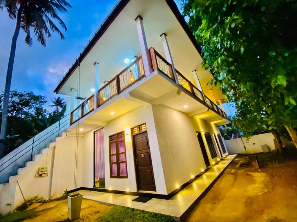 une maison blanche avec un escalier sur son côté dans l'établissement Milano Grand, à Matara