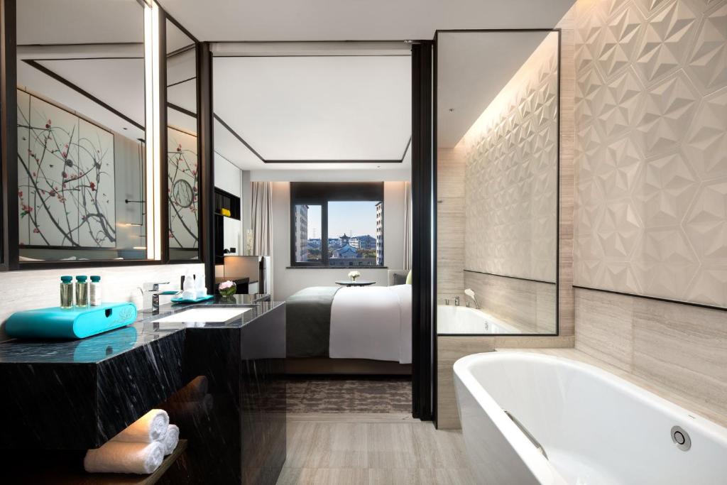 a bathroom with a tub and a bed and a bath tub at Crowne Plaza Wuzhen by IHG in Tongxiang