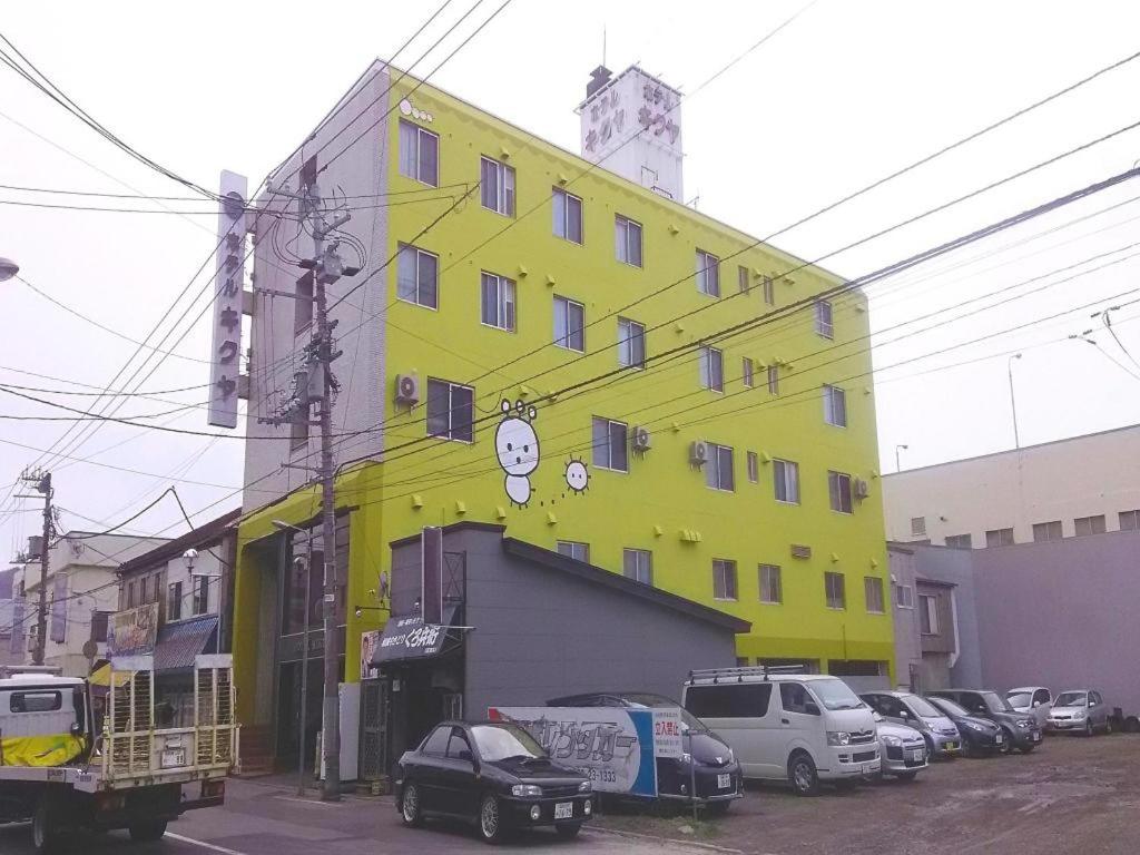 a yellow building with cars parked in front of it at Hotel Kikuya in Hakodate