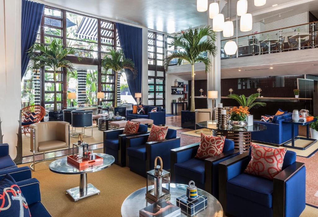 a lobby with blue chairs and tables and palm trees at Albion Hotel in Miami Beach