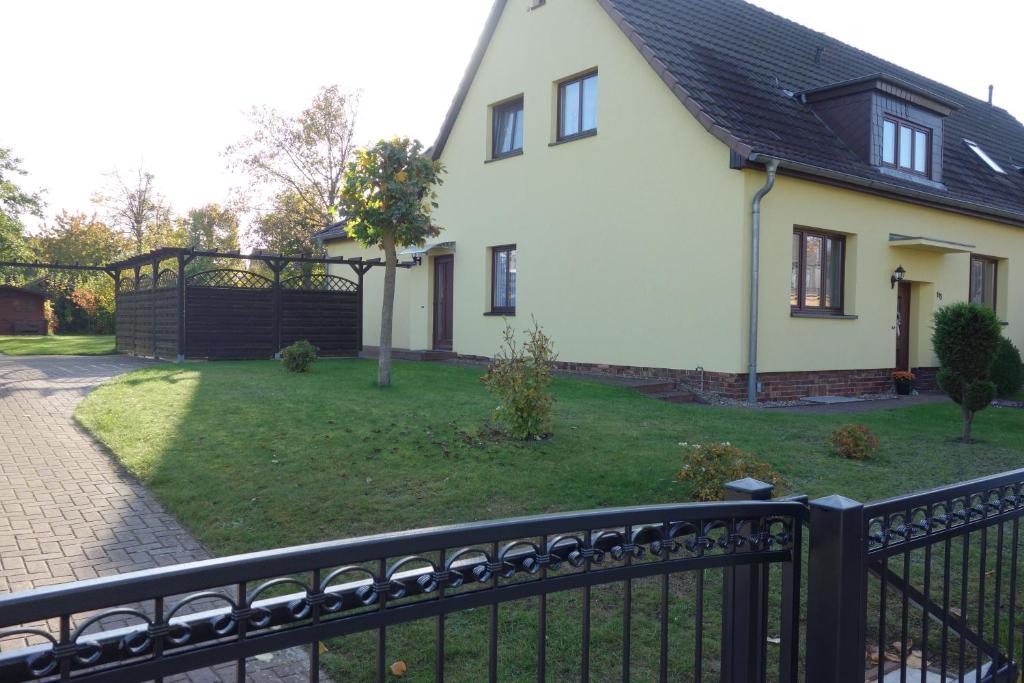 a white house with a black fence and a yard at Ferienwohnung "Meißner" in Rechlin