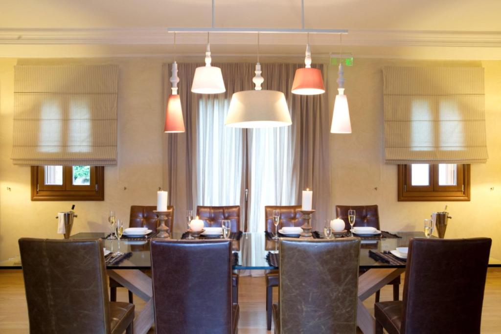 a dining room with a table and chairs and pendant lights at Villa Veneziano Suites & Villa in Nydri