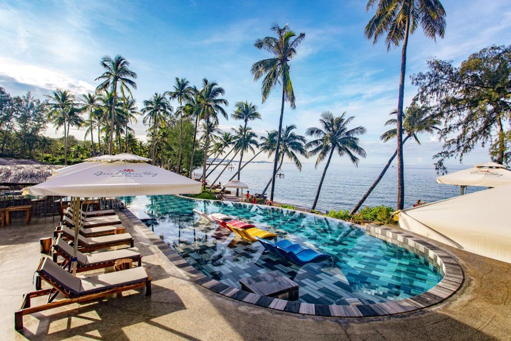 an infinity pool with chairs and umbrellas and the ocean at Grand Ocean Bay Resort Phu Quoc in Phu Quoc