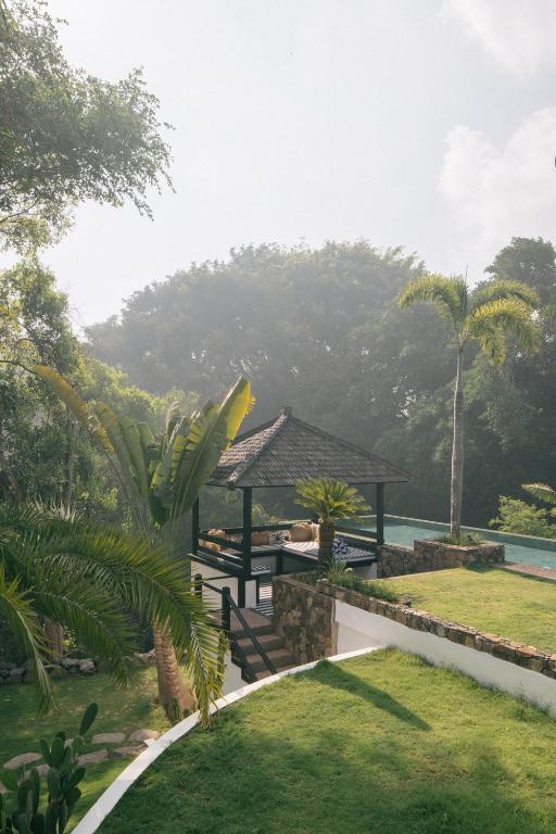 a garden with a gazebo next to a body of water at Villa Puri Greenlot Cemagi in Canggu