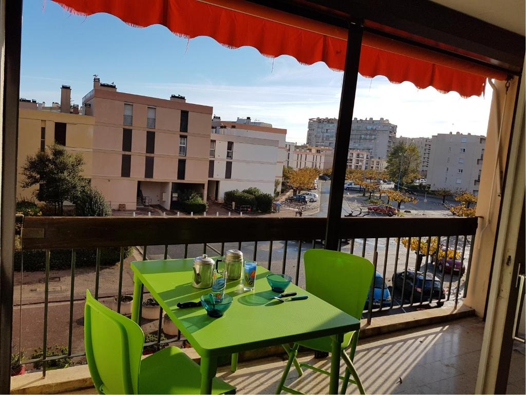 d'une table et de chaises vertes sur un balcon dans l'établissement Grand studio avec terrasse proche du port de Saint Cyprien -3RM168, à Saint Cyprien Plage