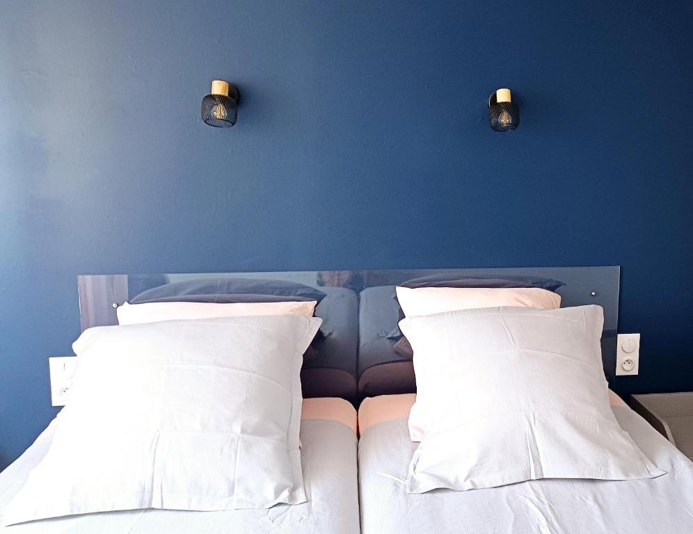 - une chambre bleue avec un lit et des oreillers blancs dans l'établissement Spacieux T3 Sète, parking, 10 min à pied gare et centre ville, wifi, clim, à Sète