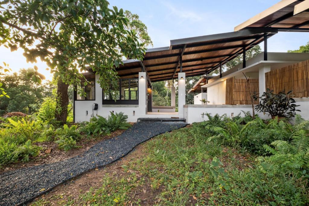 a home with a pathway leading to the front door at Casa Algarrobo relaxing farm stay in Puerto Rico in Cerro Gordo
