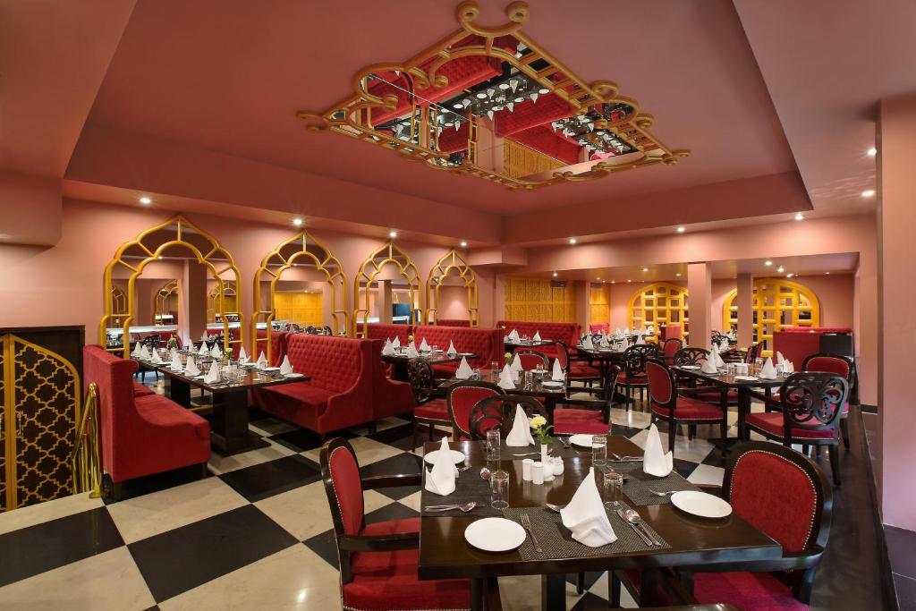 a restaurant with tables and red chairs and a chandelier at Hotel Clarks Shiraz in Agra