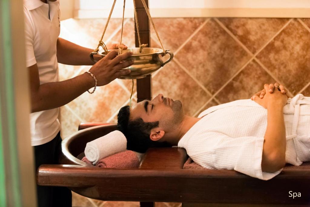 a man laying on a bed in a bath room at Hotel Clarks Shiraz in Agra