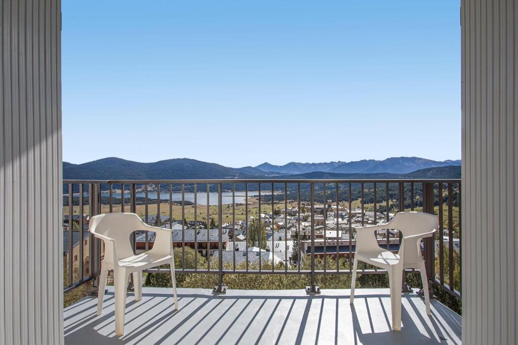 un balcon avec deux chaises et une vue sur une ville dans l'établissement EdenWeiss - Appt 6p à 1km des pistes, aux Angles
