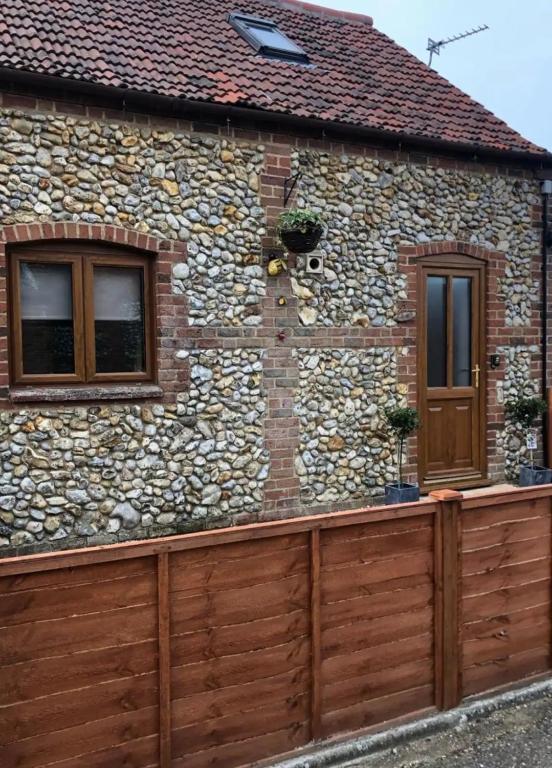 a house with a wooden fence in front of it at The Ducks - Gorgeous Norfolk Upside down Cottage - with Lazy Spa in Mileham