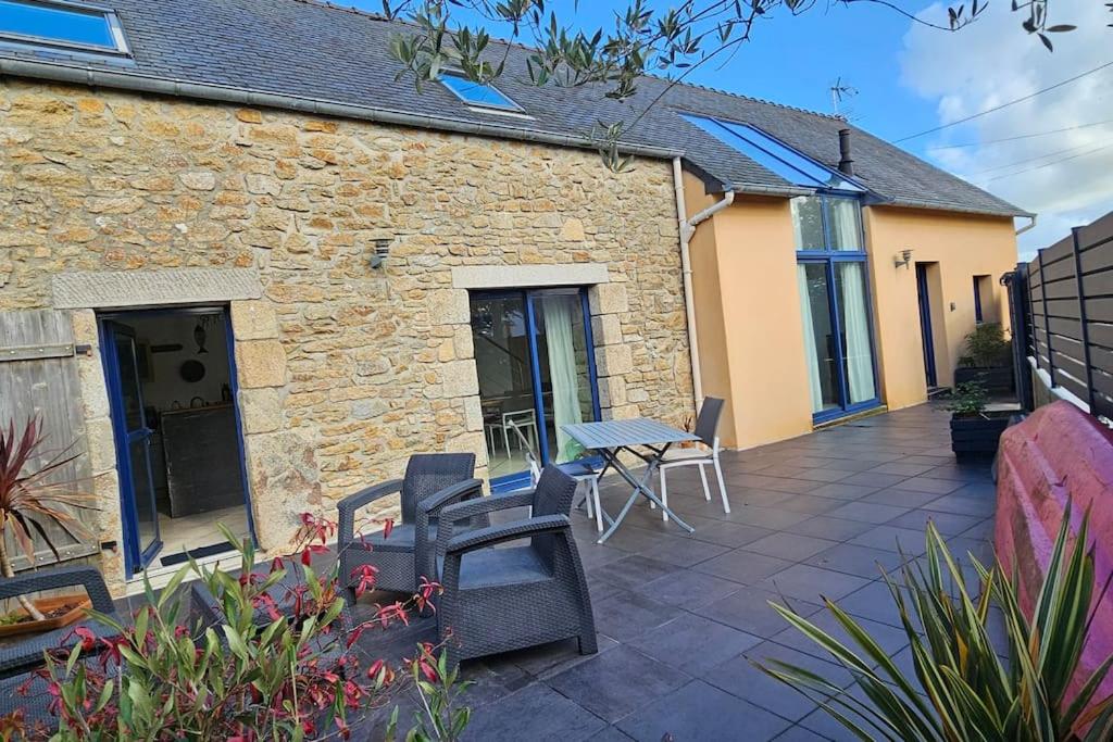 un patio avec des chaises et une table et un bâtiment dans l'établissement Charmante maison proche plages et GR34, à Perros
