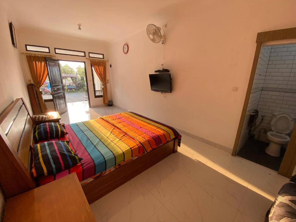 a bedroom with a bed with a colorful blanket at Kamar no 2 in Sampal 2