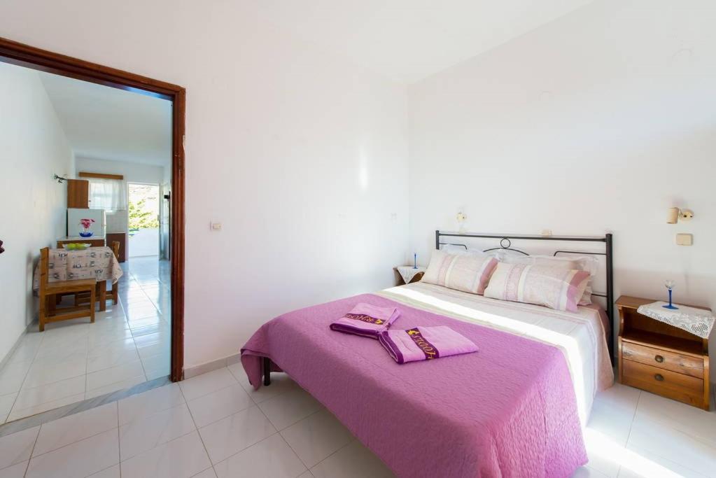 a bedroom with a large bed with a pink blanket at Merryland Studios & Apartments in Kremasti