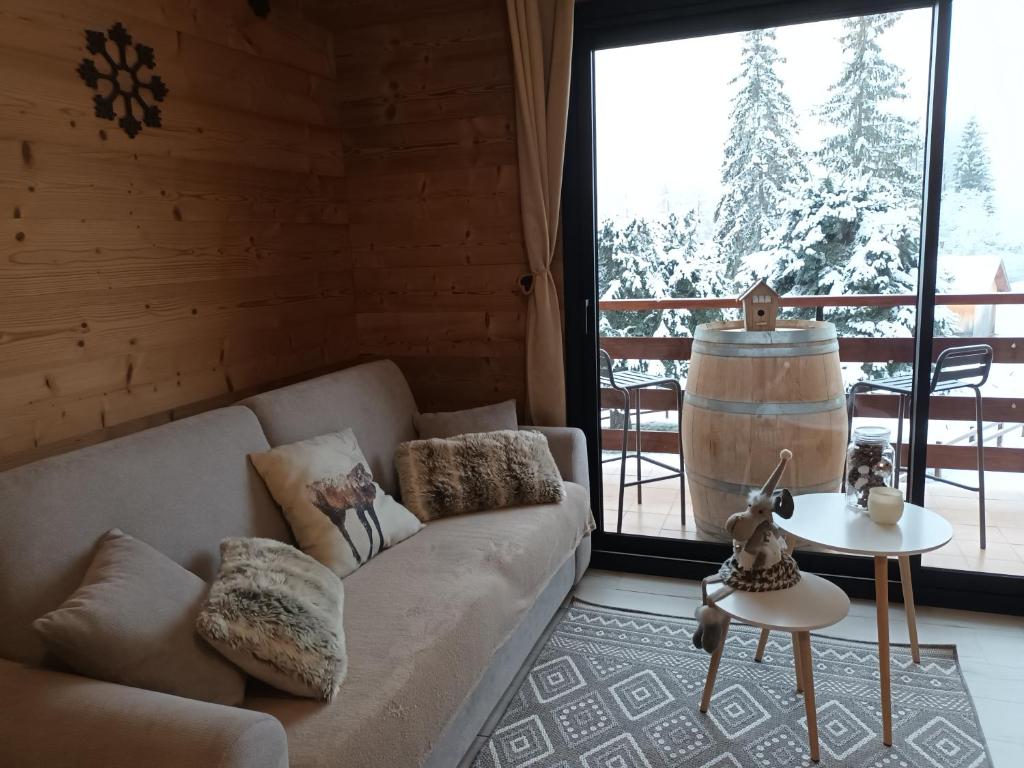 ein Wohnzimmer mit Couch und großem Fenster in der Unterkunft Appartement montagne LE FLOCON in Saint-Michel-de-Chaillol