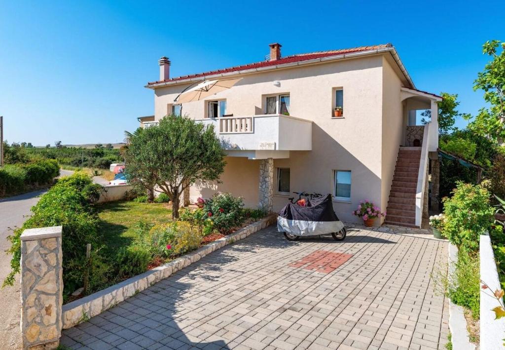 a large white house with a tiled driveway at Apartment San in Povljana